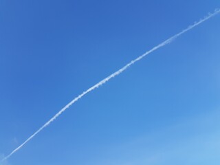 Fototapeta na wymiar White trail of an airplane in the blue sky