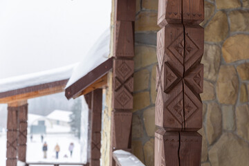 Fototapeta na wymiar View from the gazebo with carved wooden poles on the winter forest and mountains. Carved wooden elements of the gazebo or veranda of the house. wooden gazebo in winter mountain park, Carpathian.