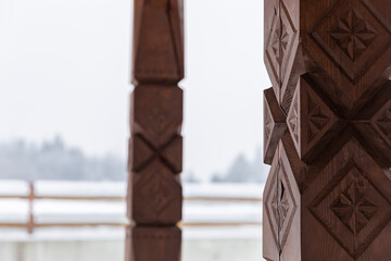 View from the gazebo with carved wooden poles on the winter forest and mountains. Carved wooden...