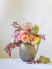 autumn flowers and berries  in rustic ceramic jug on background white  wall