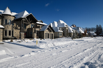 New large homes in sun after a fresh snowfall on a snowy street in Ontario Canada winter with blue...