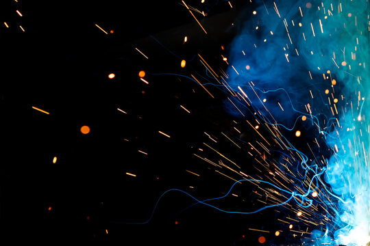 Close up view and background of the gas metal arc welding (GMAW) process with sparks, light, bokeh effect and smoke.