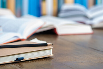 Notebook with pencil on desk with blurred soft library background