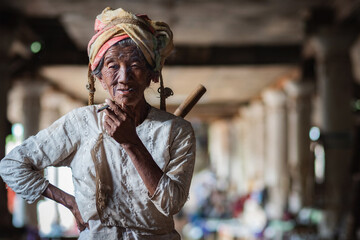 Old Burmese lady smoking a cigar at traditional market in Indein Village, Shan State, Myanmar...