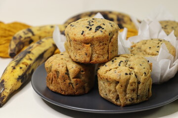 Plantain muffins. A healthy snack with extra ripe plantains, whole wheat flour and sesame seeds as the ingredients. Shot with muffins inside parchment paper cups
