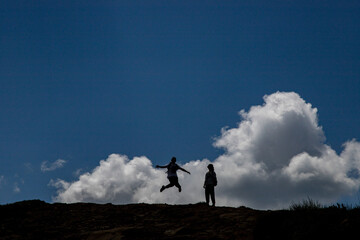 Two Teen Girls Jumping on the Top of Mountain