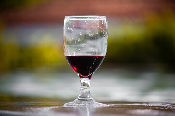 Glass of red wine standing at the edge of the swimming pool