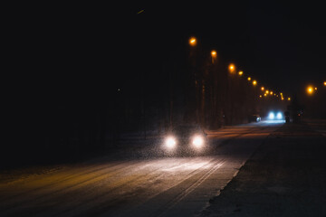 Cars in a snowstorm at night on the road in winter. Traffic in winter. Defocused