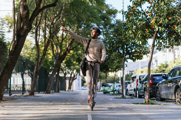 Fototapeta premium African-american man with turtleneck vest enjoying a ride with his electric scooter and pointing with his arm