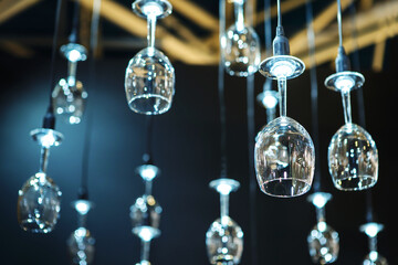 LED-lit glass wine glasses hang from the ceiling like small chandeliers. Unusual lighting solution. selective focus