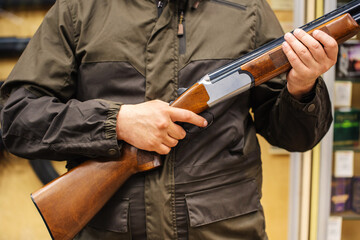 A man holds a shotgun in his hands, finger on the trigger. Double-barreled firearms for bird...