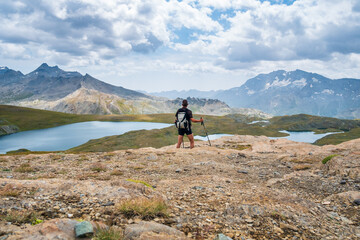 Hiker looking at view of idyllic blue alpine lake high up on the mountains, scenic landscape rocky terrain at high altitude on the Alps, fitness wellbeing freedom concept