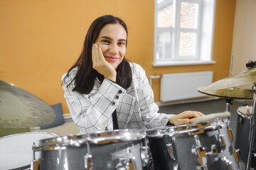 Portrait of a young beautiful adult woman behind a drum kit. Hobbies and pastime.