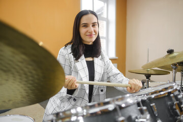 Portrait of a young beautiful adult woman behind a drum kit. Hobbies and pastime.