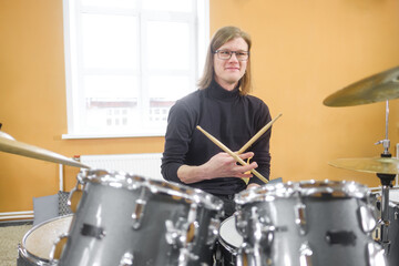 Young adult men and women learn to play drums at school. Hobbies and pastime.
