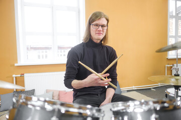 Young adult men and women learn to play drums at school. Hobbies and pastime.