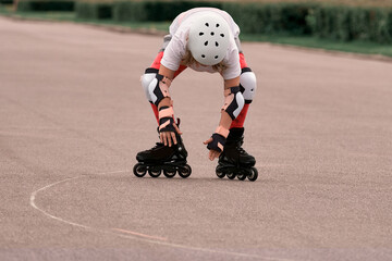A girl roller skater in protection gets up on roller skates after a fall. Failure in training.