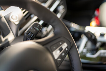 Widok wnętrza samochodu z widokiem części kierownicy w centralnie umieszczonym elementem odpowiedzialnym za regulację prędkości wycieraczek. oraz dźwignią, która uruchamia spryskiwacz z płynem.