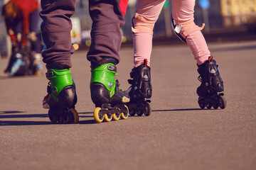 Father teaches his daughter to roller skate on the streets of the city. The family goes in for sports outdoors.