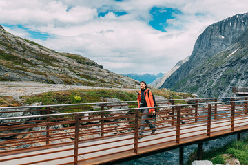 Fototapeta na wymiar Trollstigen, Andalsnes, Norway. Young Caucasian Woman Tourist Traveler Walking Viewing Platform Near Visitor Centre. Famous Landmark And Popular Destination. Norwegian County Road 63.