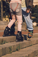 The father teaches the child to go down the stairs on roller skates. Overcoming obstacles.