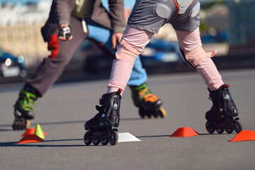 Obraz premium Child learns to roller skate in the city. The coach is filming a student on roller skates.