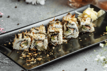 Golden dragon sushi roll with tuna, eel, cucumber, sesame seeds and tobiko caviar on wood background
