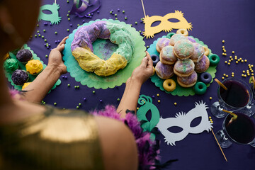 Close-up of woman setting the table for Mardi Gras celebration and serving King cake.