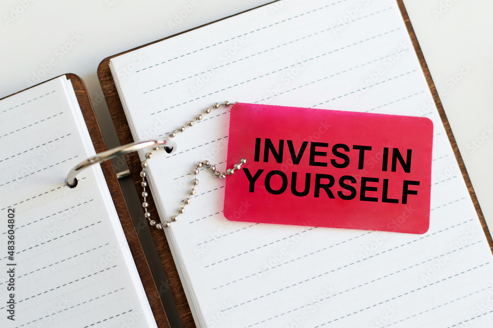 Poster business and finance concept. invest in yourself text on a red card on the background of a notebook 