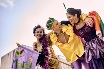 Happy multiracial friends in carnival costumes have fun on Mardi Gras celebration parade.