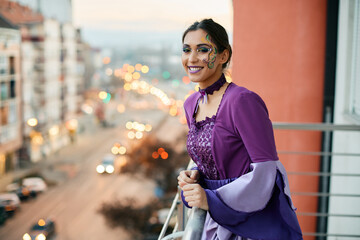 Happy woman in carnival costume watching Mardi Gras street parade from her balcony. © Drazen