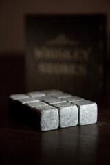Set of whiskey chiller grey soapstone stones close up on the dark wooden background. Shallow depth of field vintage style picture