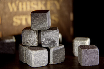 Set of whiskey chiller grey soapstone stones close up on the dark wooden background. Shallow depth of field vintage style picture