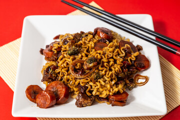 Um prato branco com uma porção de yakisoba de legumes com molho de soja. Yakisoba vegetariano...