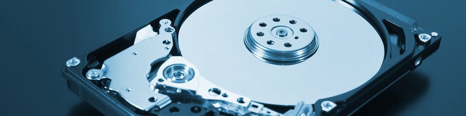 A disassembled open hard disk drive HDD of a computer or laptop lies on a dark matte surface. IT&C...