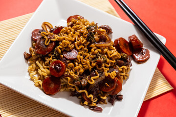 Um prato branco com uma porção de yakisoba de legumes com molho de soja. Yakisoba vegetariano...