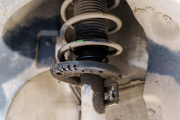 Old failed car shock absorber. Car in service is raised on lift. Replacement with new shock...