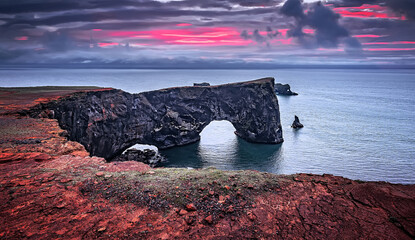 Majestic large arch of lava on the coast in Atlantic Ocean during sunset. Amazing Icelandic...