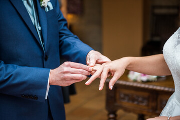 Obraz premium Groom putting ring on bride's hand, symbol of love, on their wedding day. Wedding concept