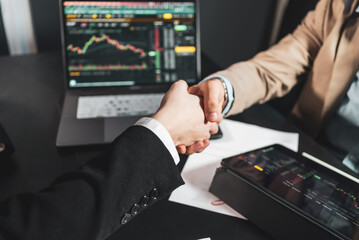 Businessmen shaking hands in the office with computer