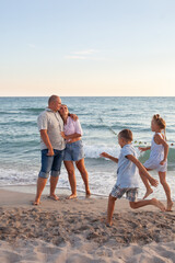 portrait of a big happy family, parents with children are relaxing on the seashore