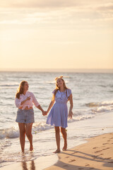 Mom and her teenage daughter hugging and smiling together over blue sea view
