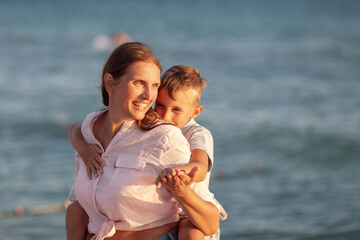 Mom and her son hugging and smiling together over blue sea view