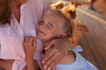 Happy mother and daughter in a cafe on the seashore, a woman with a child hugging, laughing