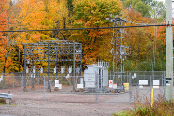 Fenced electrical substation with colourful autumn trees in background