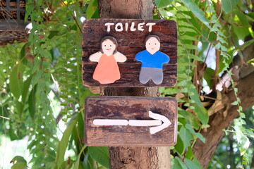 Wood sign outdoor indicating the way to the bathroom or toilet. woman and man cartoon design.