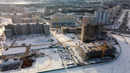 Construction site of a modern city block. High-rise buildings under construction. Construction tower cranes. Construction site in winter. Aerial photography at sunset.