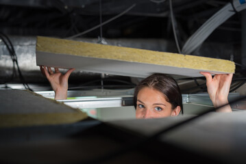 Woman lowering insulated board back into ceiling