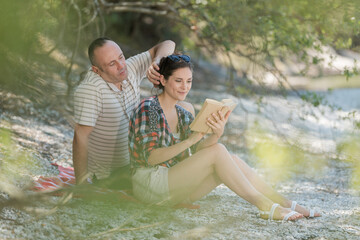 couple reading book and newspaper by a lake