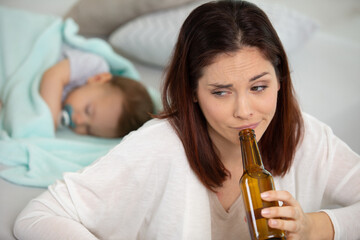 woman is drinking beer while baby is sleeping